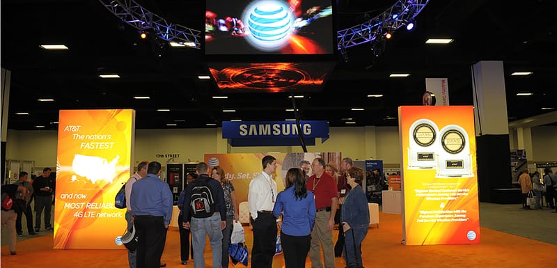 Large tradeshow booth with digital graphics hanging from the ceiling, duratrans, and lounge area.