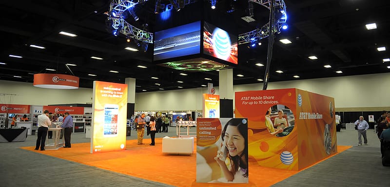 Large tradeshow booth with digital graphics hanging from the ceiling, duratrans, and lounge area.